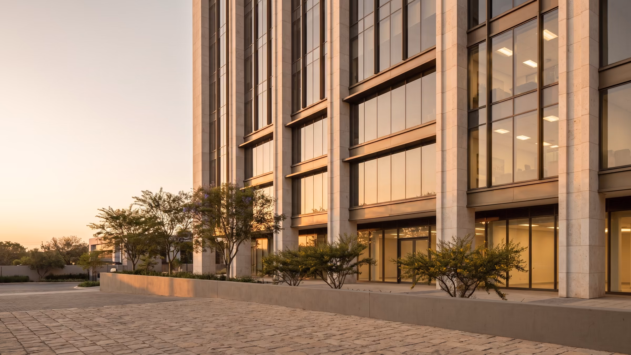 A modern commercial building with tall glazed windows at dusk
